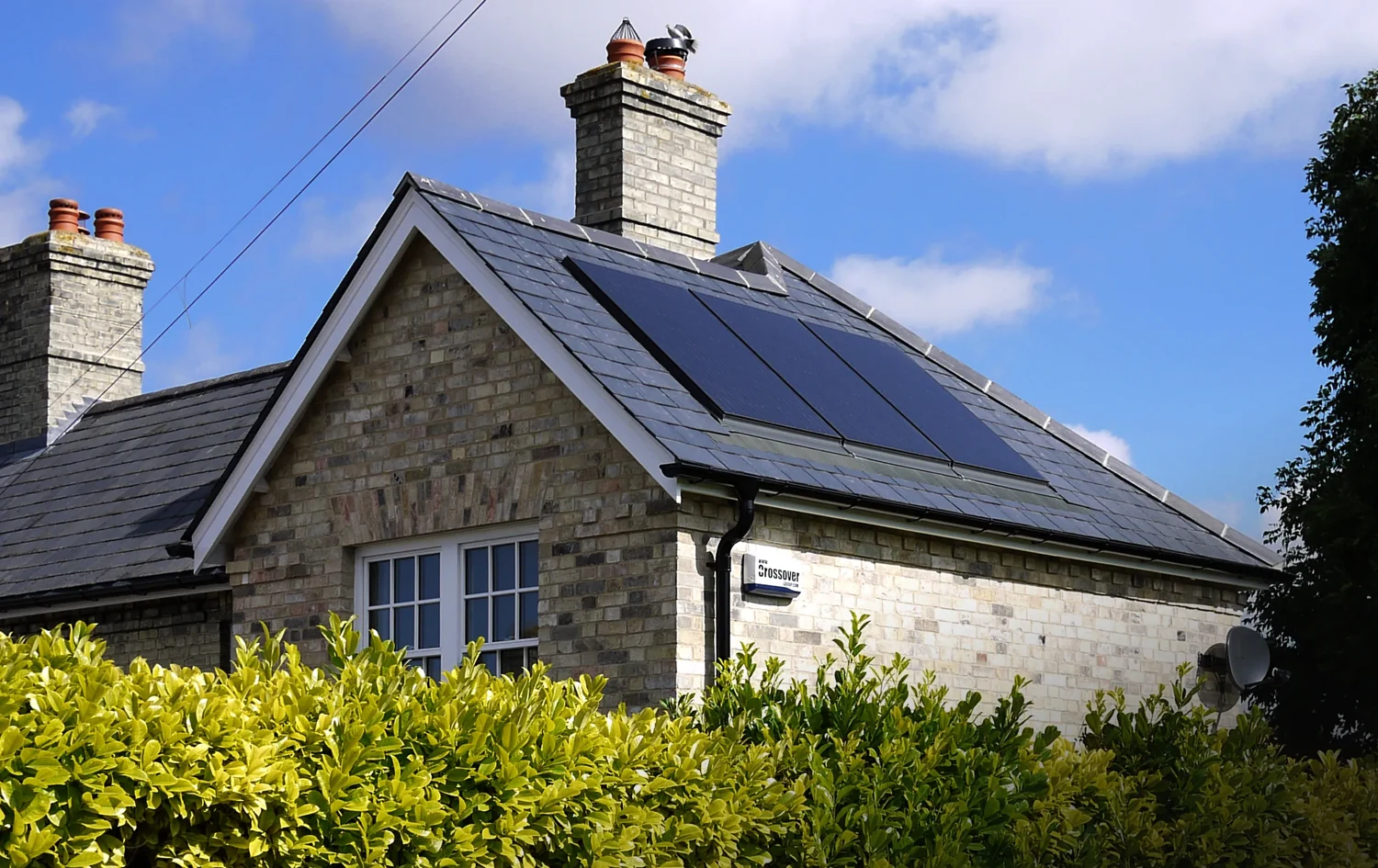 Traditional UK brick home with a pitched slate roof, chimney and modern black solar panels